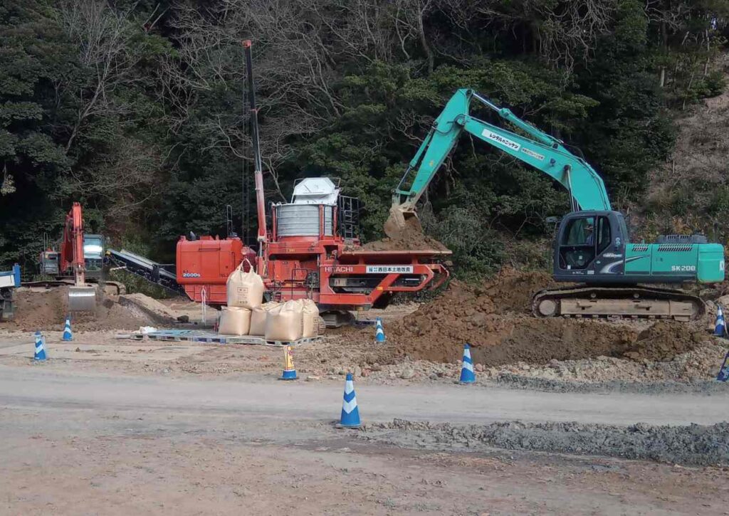 ショベルカーから自走式土地改良機へ土を運び入れる様子